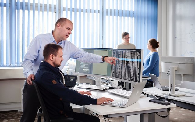 Security Operation Center Zwei Mitarbeiter bei der Arbeit sprechen über eine Darstellung am Bildschirm