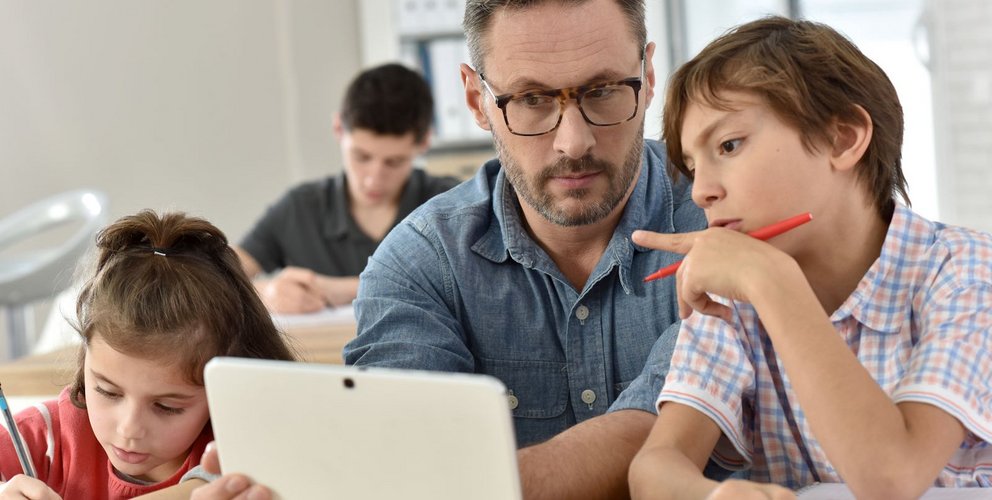 Lehrer mit Schülern am Tablet