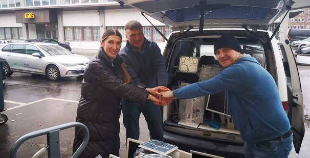 Drei Personen räumen Hardware in einen Transporter