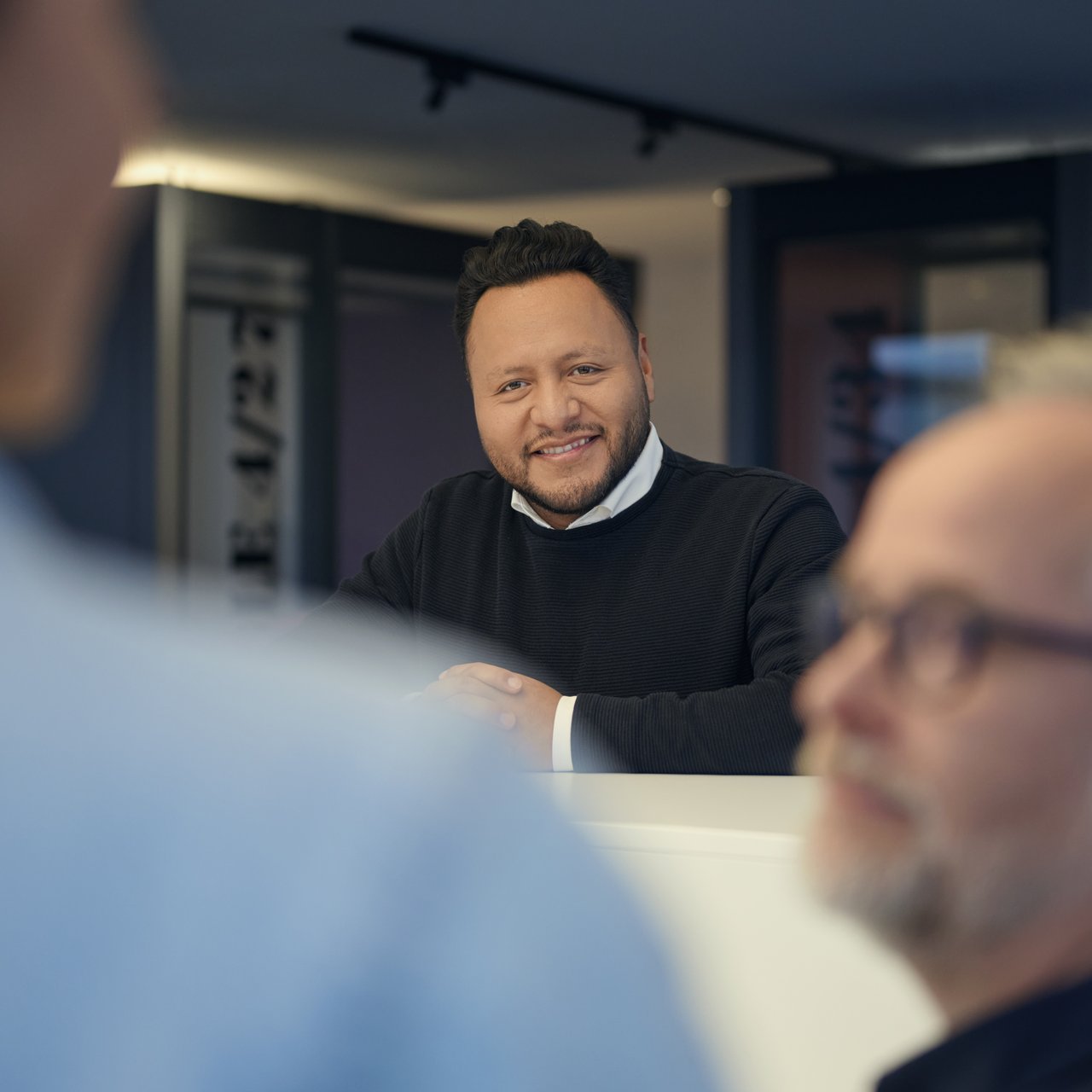 Dataport-Mitarbeiter in der IT-Administration begrüßt Kolleg*innen im Büro