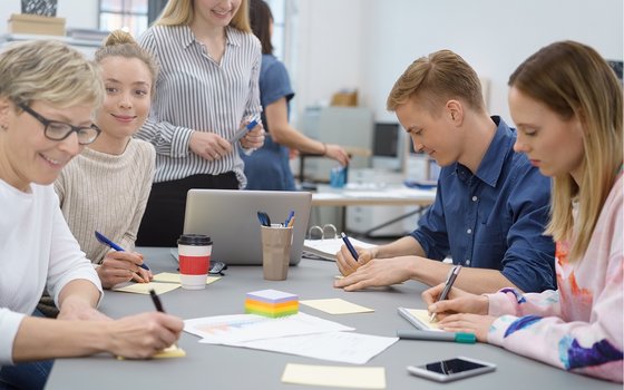 Brainstorming: Menschen um einen Tisch machen Notizen auf Post-Its