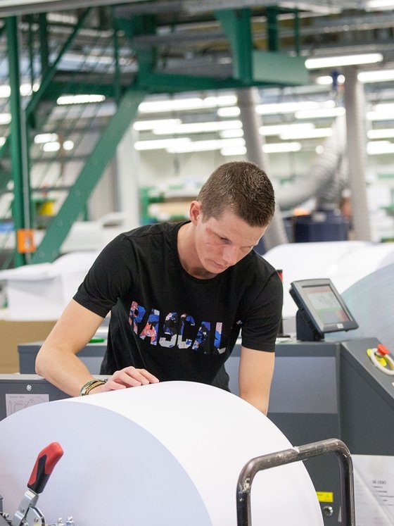 Ein Mann arbeitet an einer Papierrolle im Druckzentrum