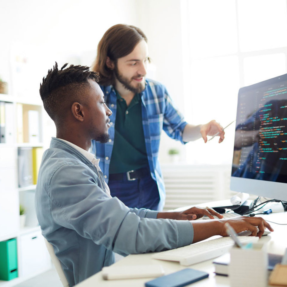 Zwei Programmierer blicken im Büro auf einen Bildschirm