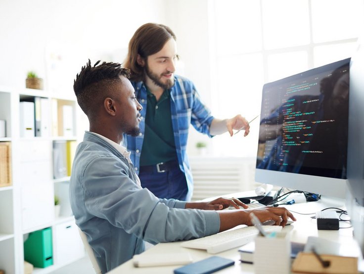 Zwei Programmierer blicken im Büro auf einen Bildschirm