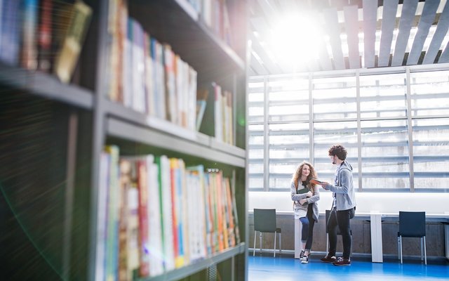 Open Source Bücherregal und Studenten in einer Bibliothek