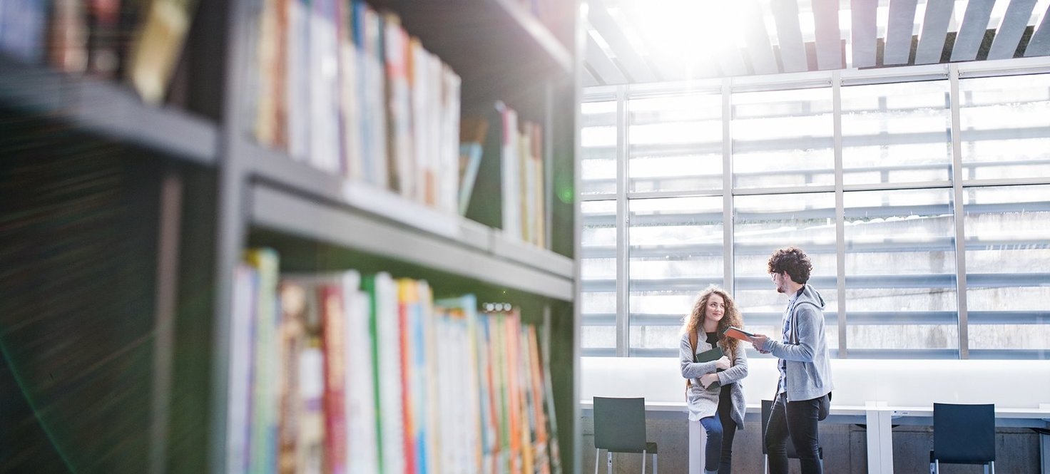 Bücherregal und Studenten in einer Bibliothek