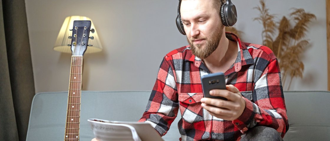 Ein junger Musiker lernt Noten mithilfe eines Smartphones