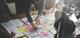 Zwei Personen an einem Tisch mit Projektunterlagen und zahlreichen Post-Its darauf