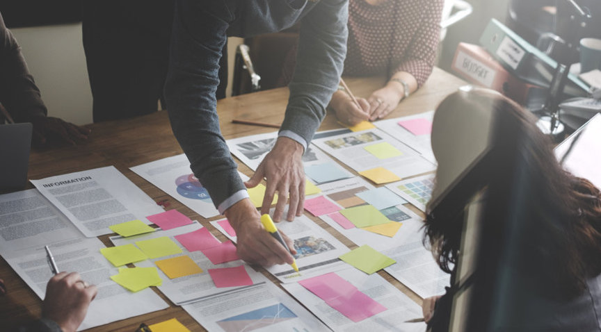Zwei Personen an einem Tisch mit Projektunterlagen und zahlreichen Post-Its darauf