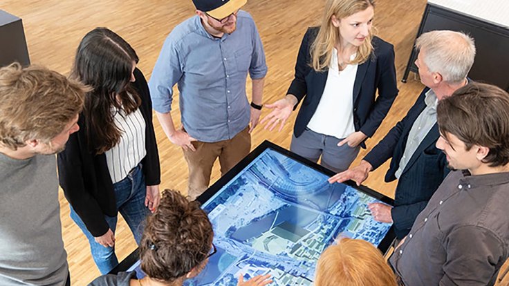 Menschen stehen um eine virtuelle Karte herum.