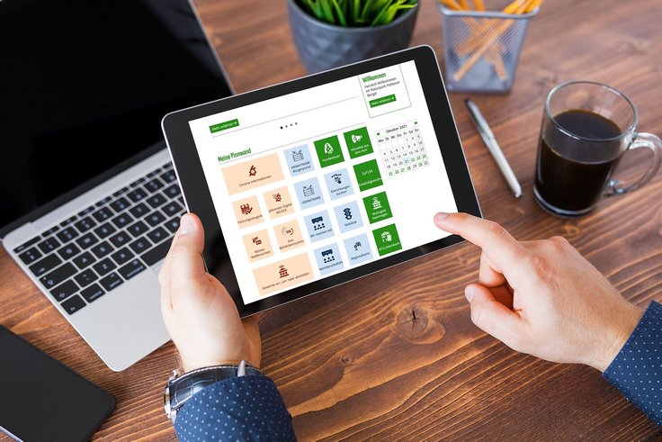 Jemand hält ein Tablet in Händen und benutzt das Bürgerportal Amt Hüttener Berge.