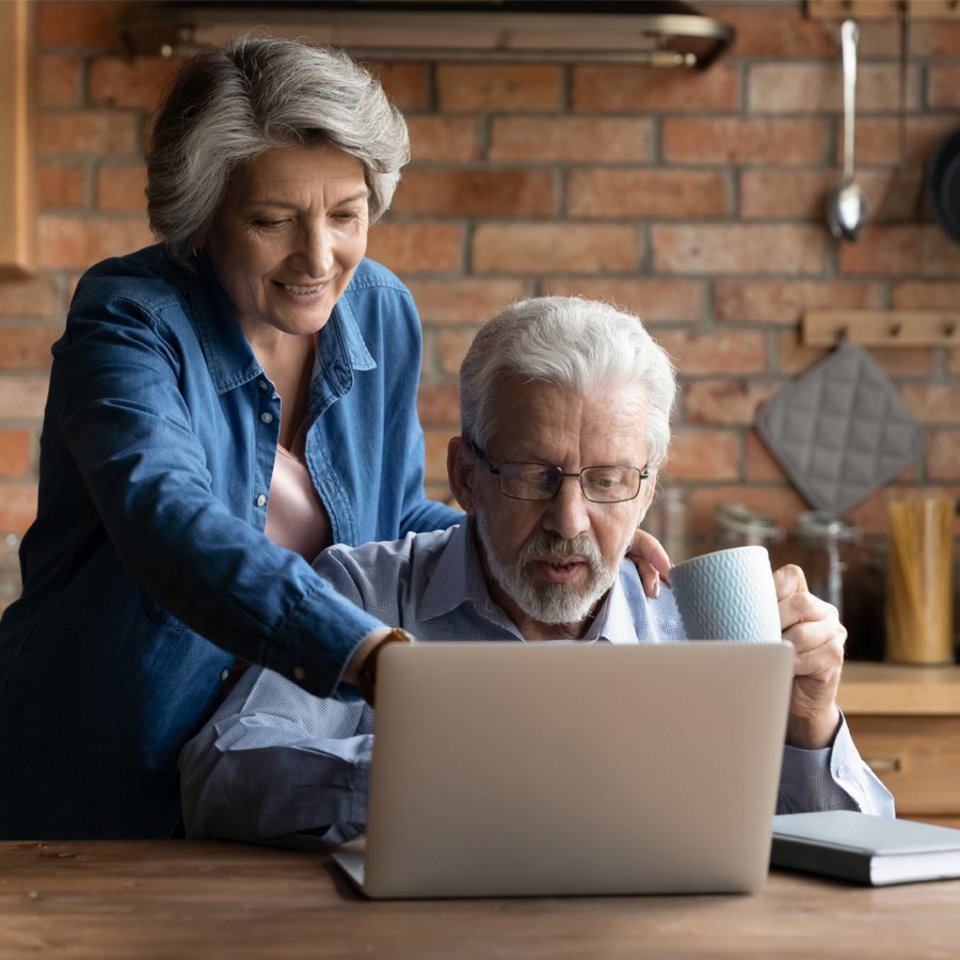 Älteres Ehepaar nutzt am Laptop-Bildschirm einen EfA-Bürgerdienst.