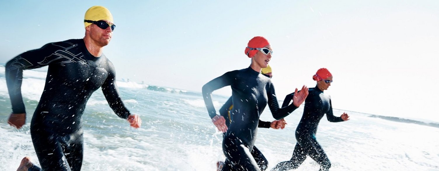 Triathlet*innen rennen durchs Wasser