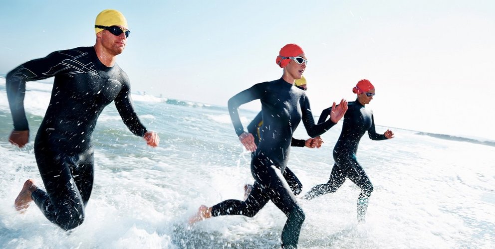Triathlet*innen rennen durchs Wasser