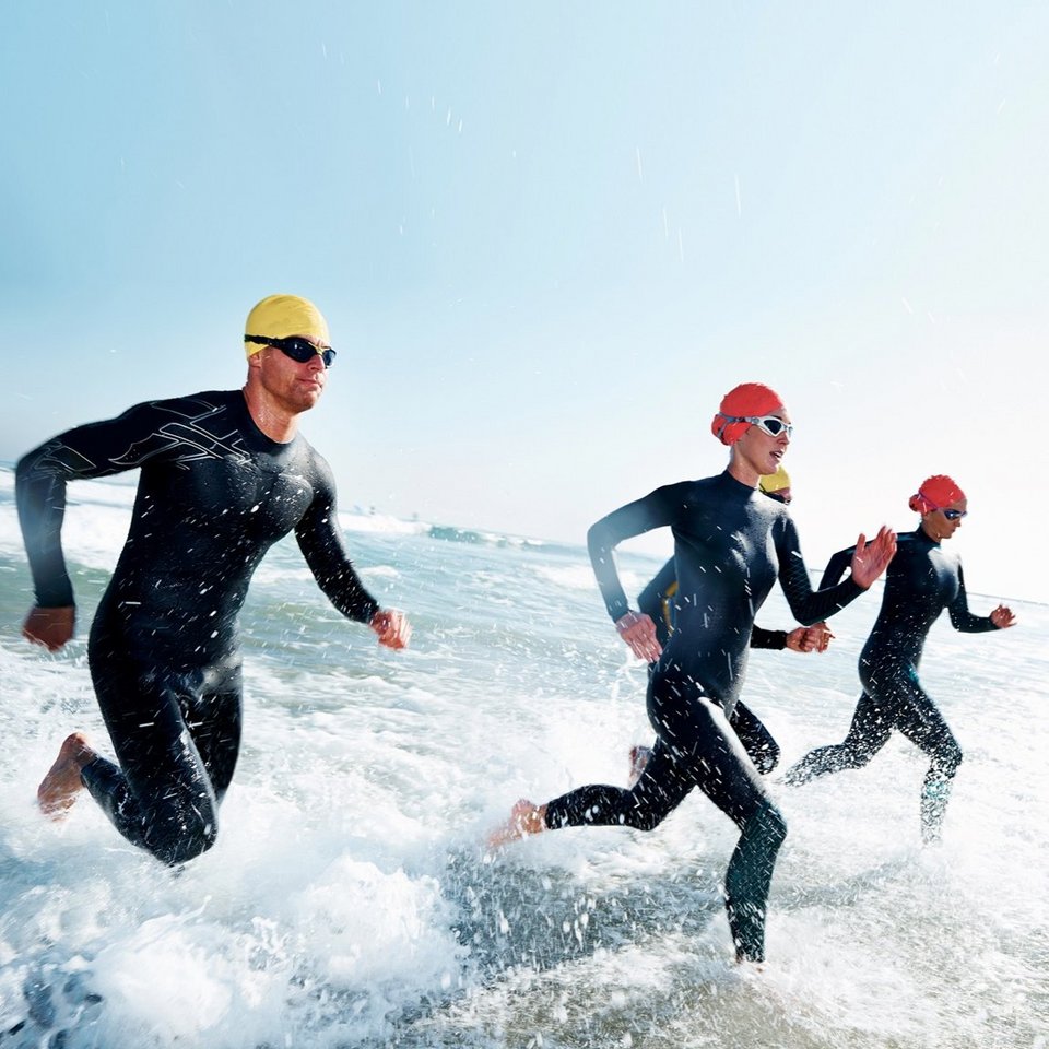 Triathlet*innen rennen durchs Wasser