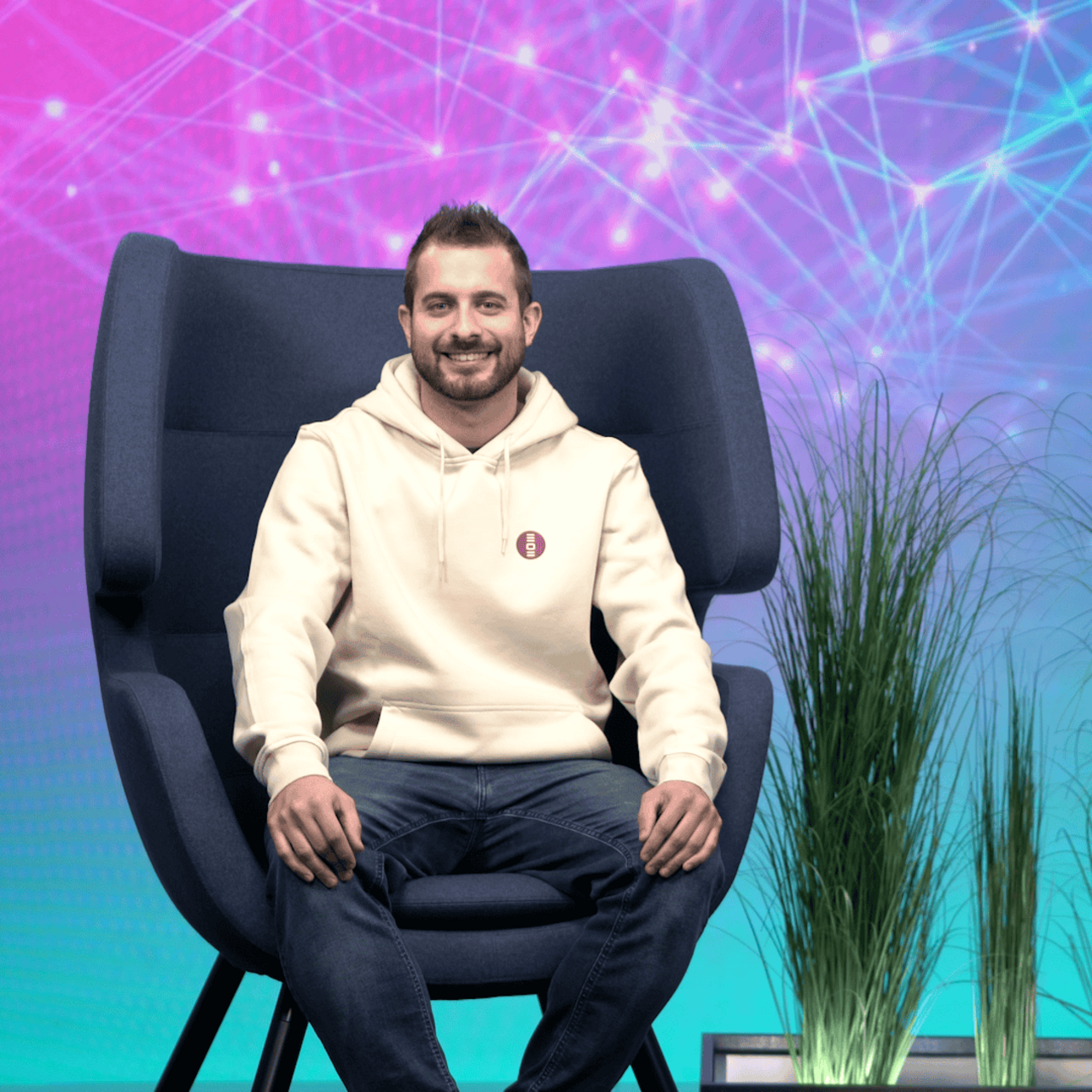 Dataport-Mitarbeiter sitzt auf einem Sessel und chelt in die Kamera