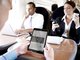 Geschäftsleute sitzen im Zug und nutzen mobile Endgeräte