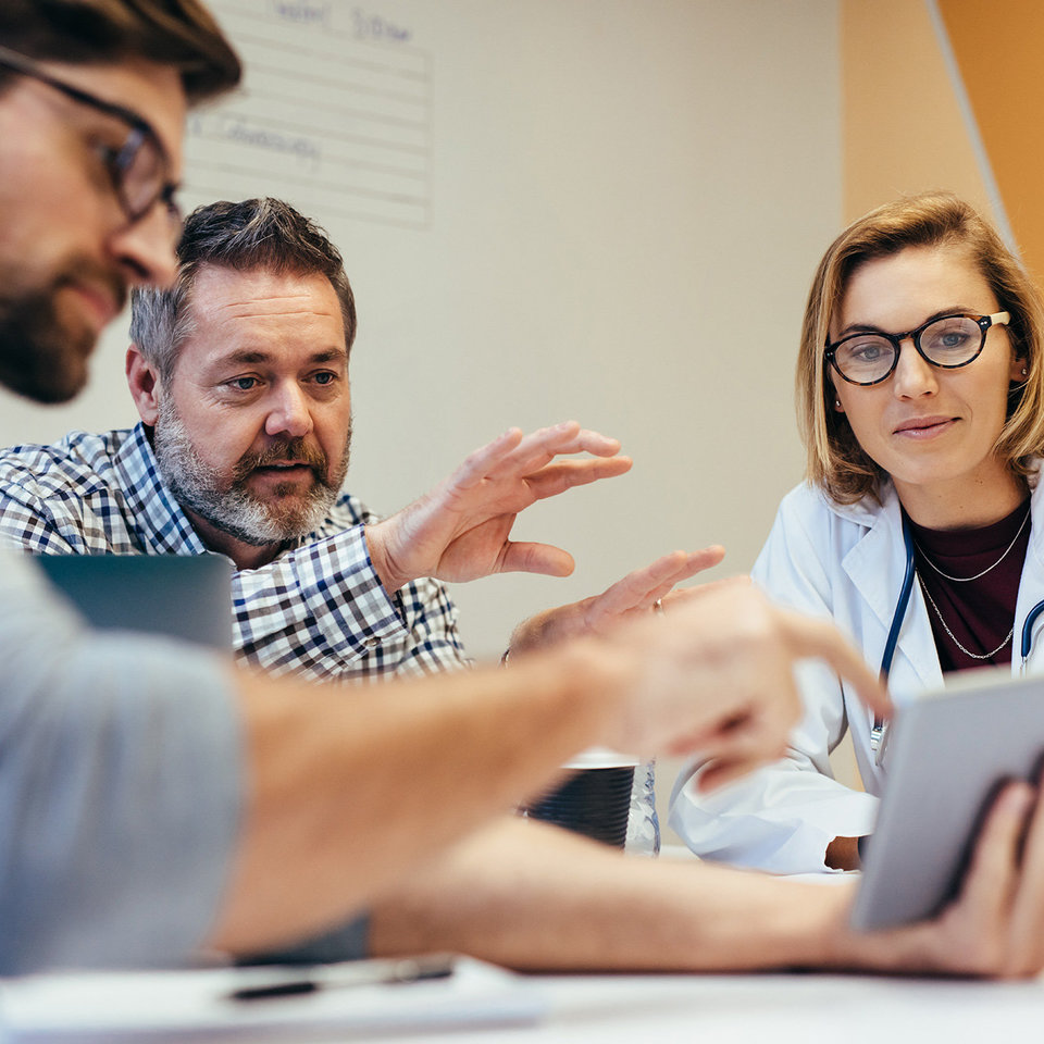 Menschen diskutieren an einem Tablet Gesundheitsthemen