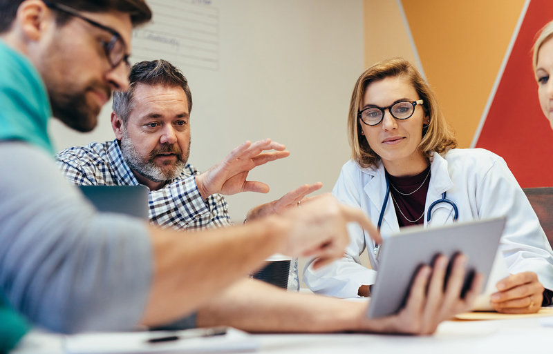 Menschen diskutieren an einem Tablet Gesundheitsthemen