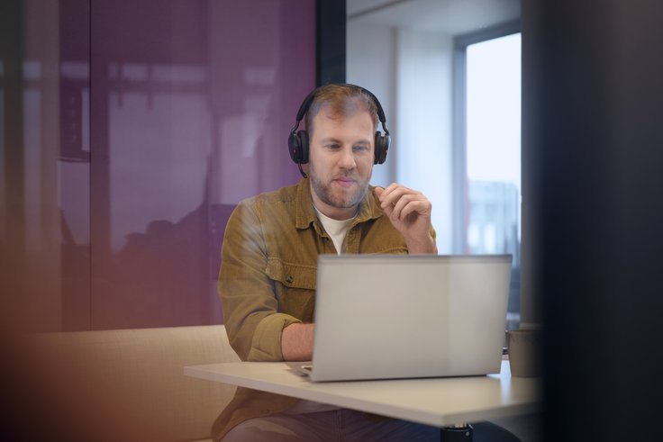 Moderne IT-Arbeitsplätze bei Dataport Dataport-Mitarbeiter mit Headset arbeitet an Laptop in der IT-Administration