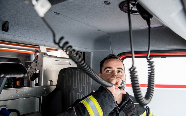 Feuerwehrmann im Wagen bei der Benutzung des Funkgerätes