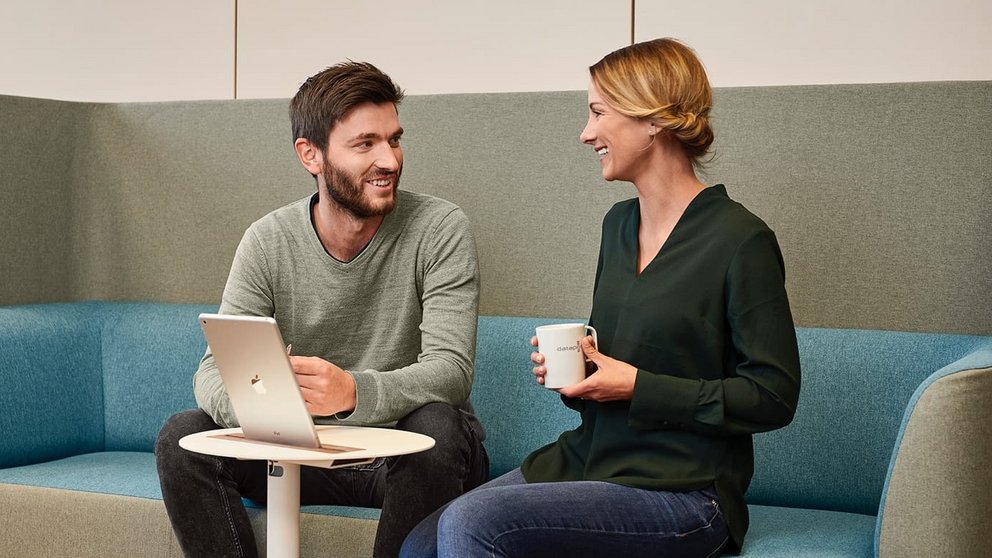 Zwei Mitarbeiter*innen unterhalten sich in der Lounge