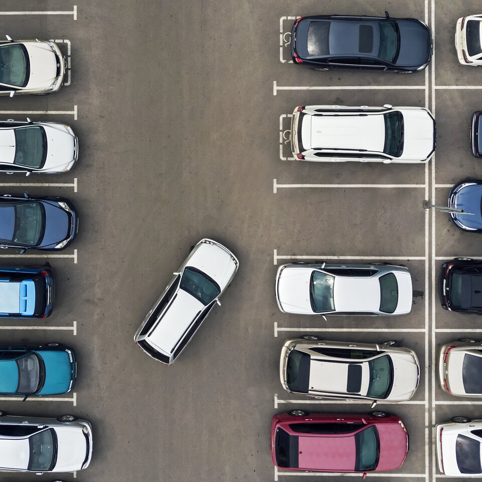dParkingPartner: Ein helles Fahrzeug versucht auf einem vollen Parkplatz einzuparken