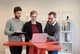 Drei Personen blicken auf Laptop und tauschen sich aus