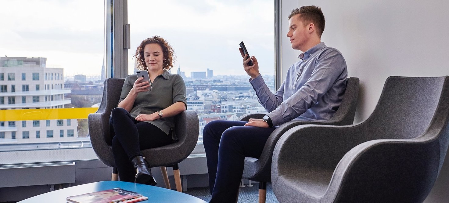 Zwei Personen an Handy und Laptop im Wartezimmer