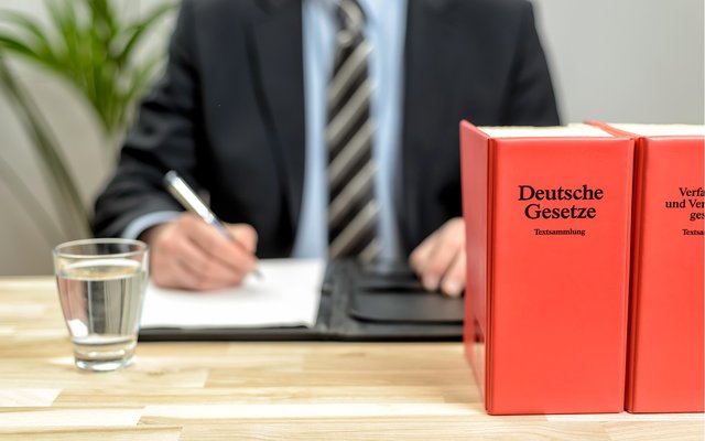 Data Center Justiz Mann mit Hemd und Krawatte am Schreibtisch mit deutschem Gesetzbuch
