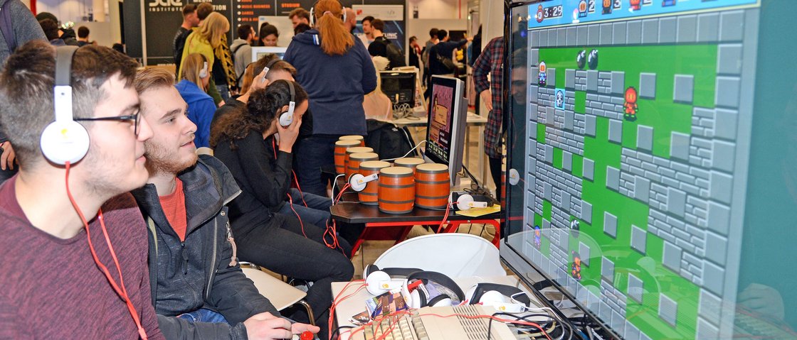 Zwei Gamer sitzen vor einem Bildschirm und spielen ein Computerspiel