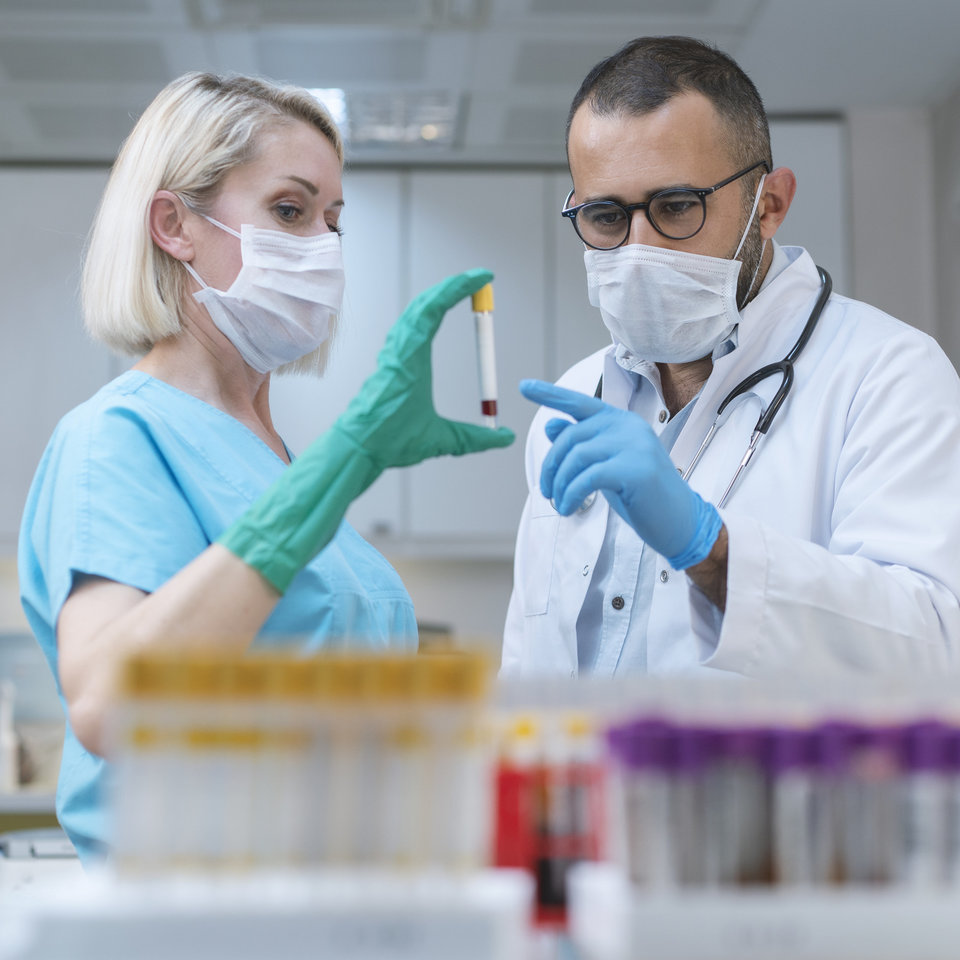 Zwei Medizinisch-Technische Assistent*innen (MTAs) untersuchen eine Blutprobe