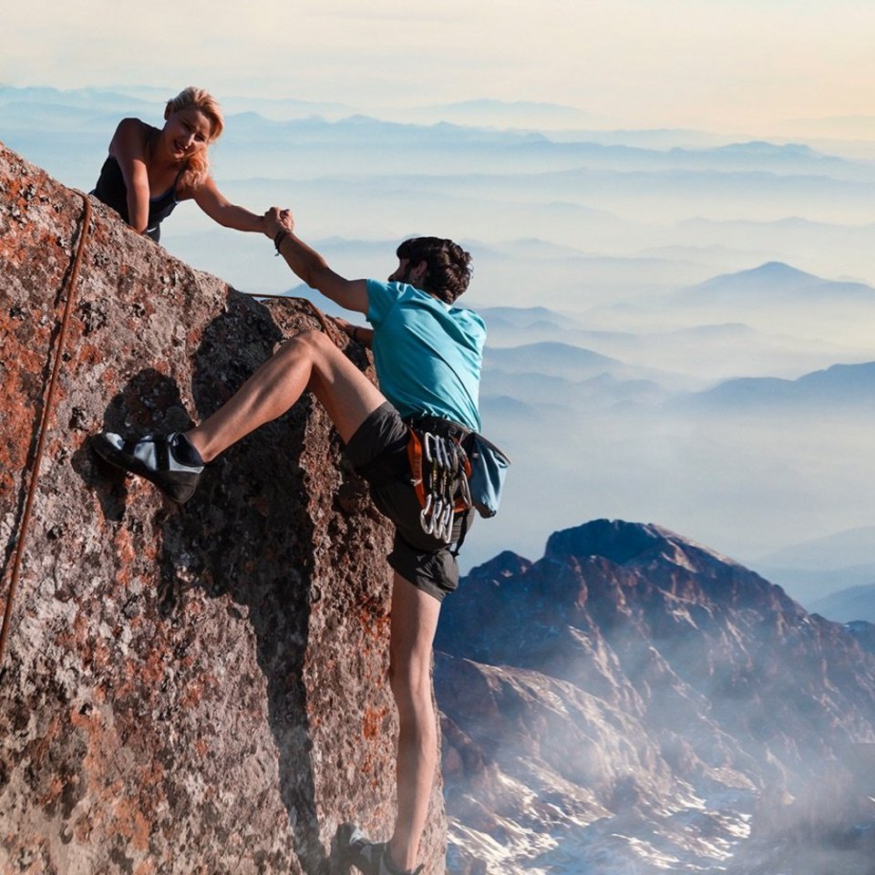 Bergsteigerin hilft ihrem Partner beim Erklimmen des Gipfels
