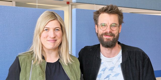 Die beiden Projektleiter Isabell Pietta und Robin Pfaff stehen vor einer blauen Wand.