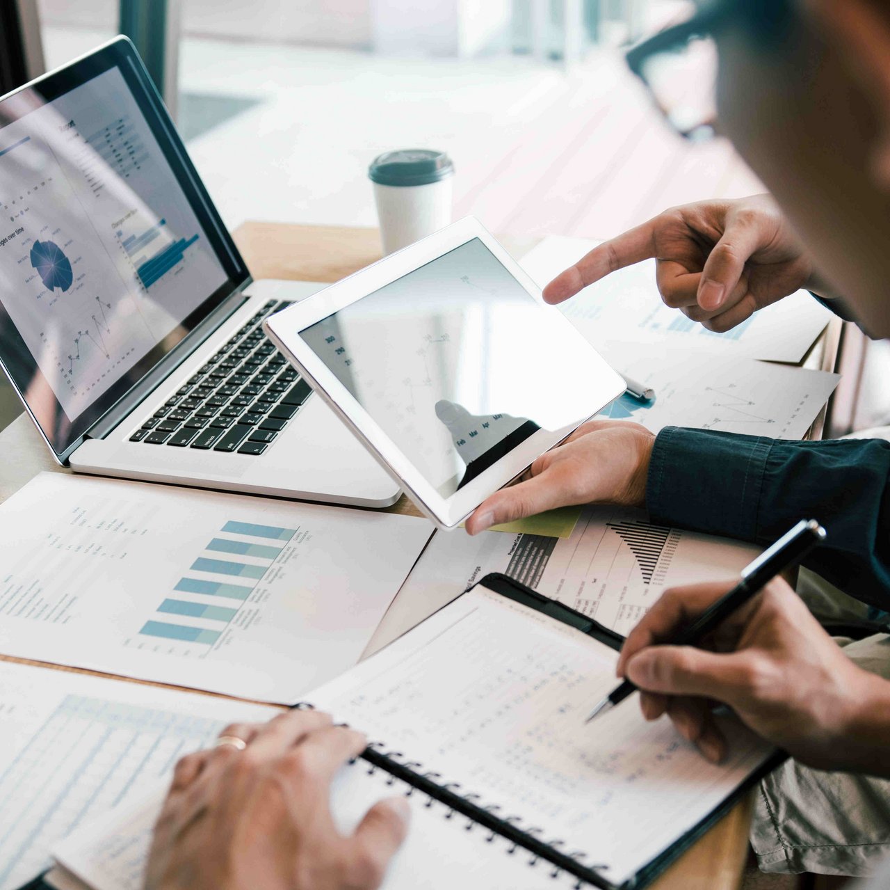 Personen sitzen am Schreinbtisch und berechnen etwas