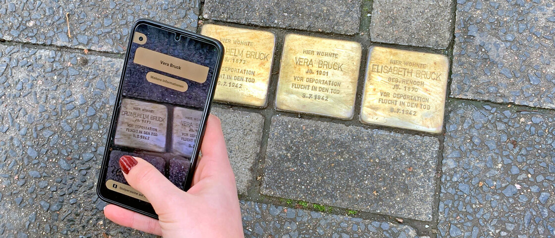 Eine Frau nutzt ihr Handy für die Augmented Reality App zu den Stolpersteinen